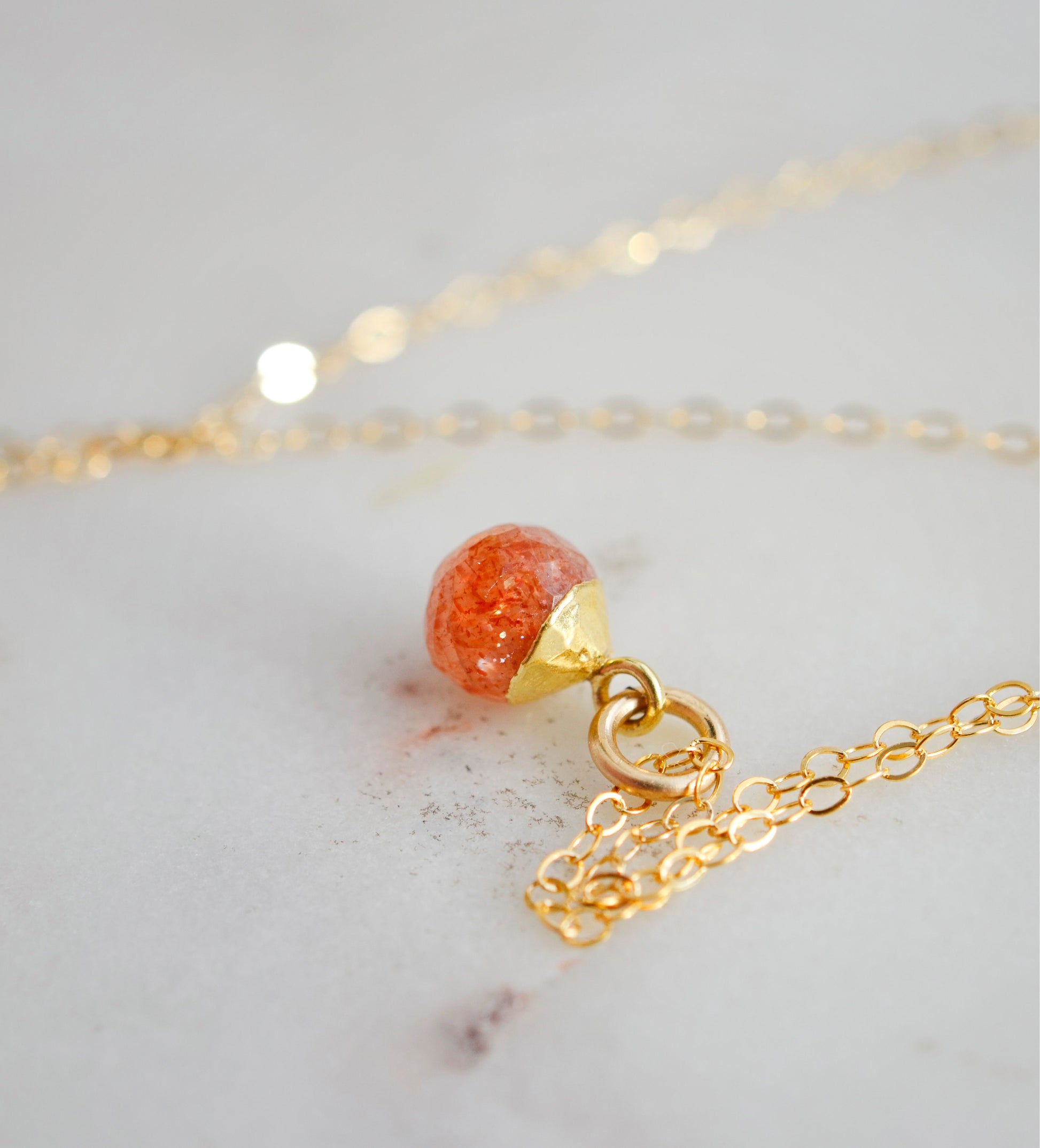 Natural orange Sunstone necklace. The stone is a faceted round and set onto a 14k gold filled chain.