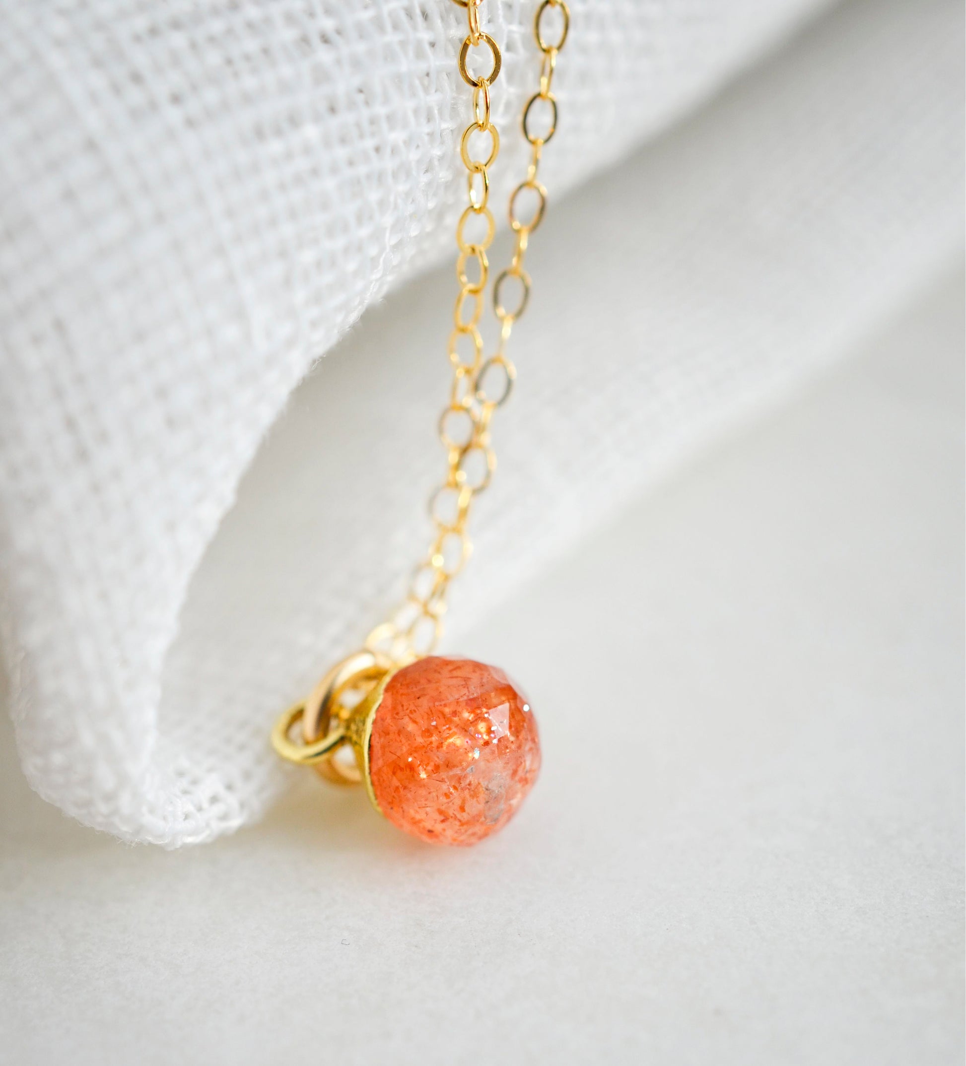 Natural orange Sunstone necklace. The stone is a faceted round and set onto a 14k gold filled chain.