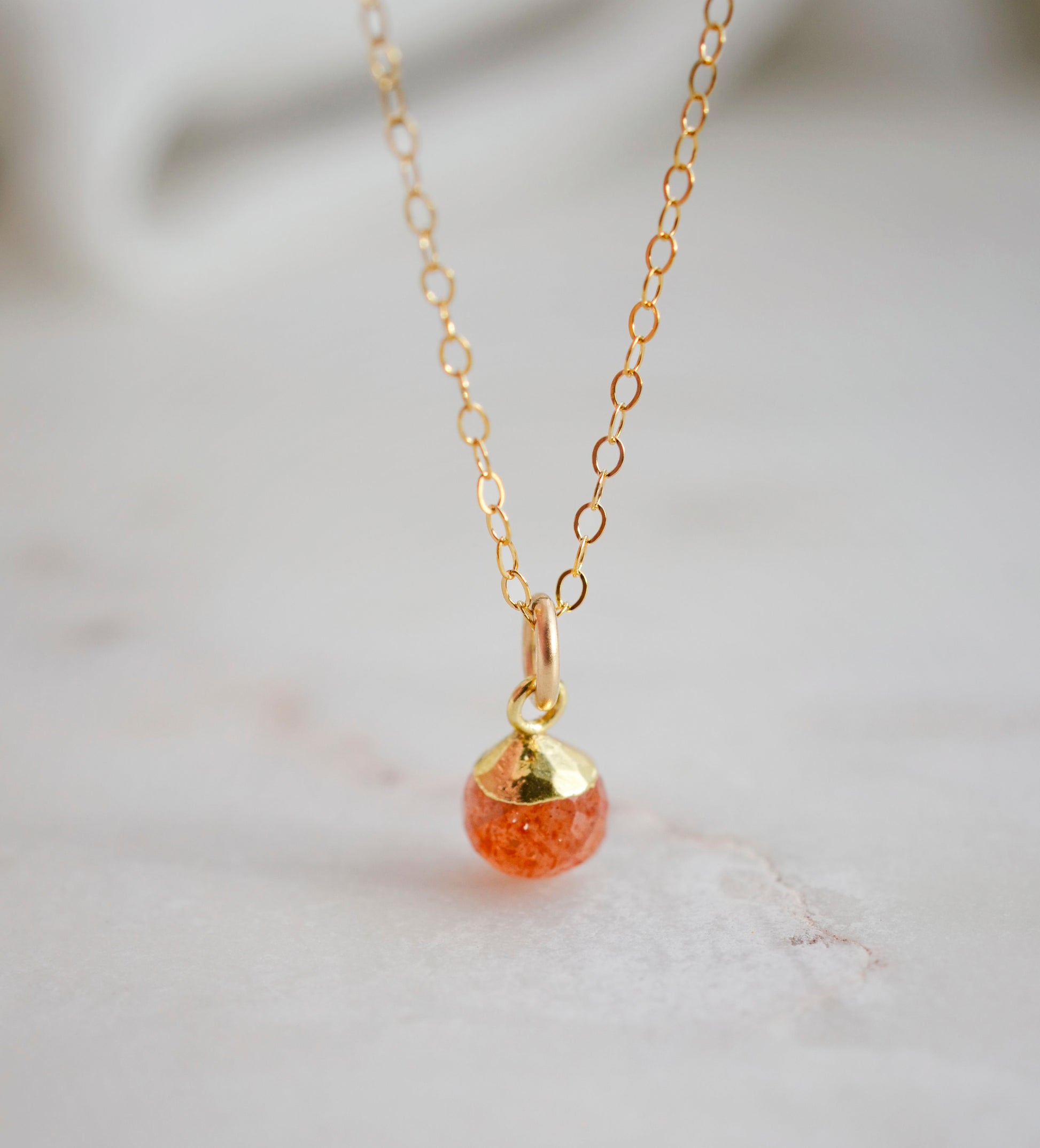 Natural orange Sunstone necklace. The stone is a faceted round and set onto a 14k gold filled chain.