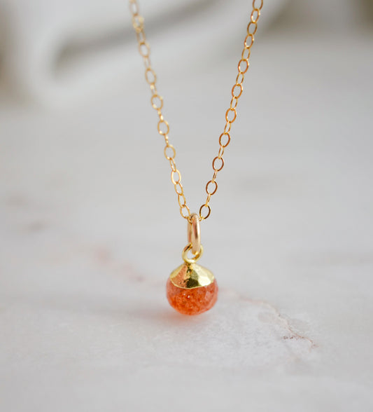 Natural orange Sunstone necklace. The stone is a faceted round and set onto a 14k gold filled chain.