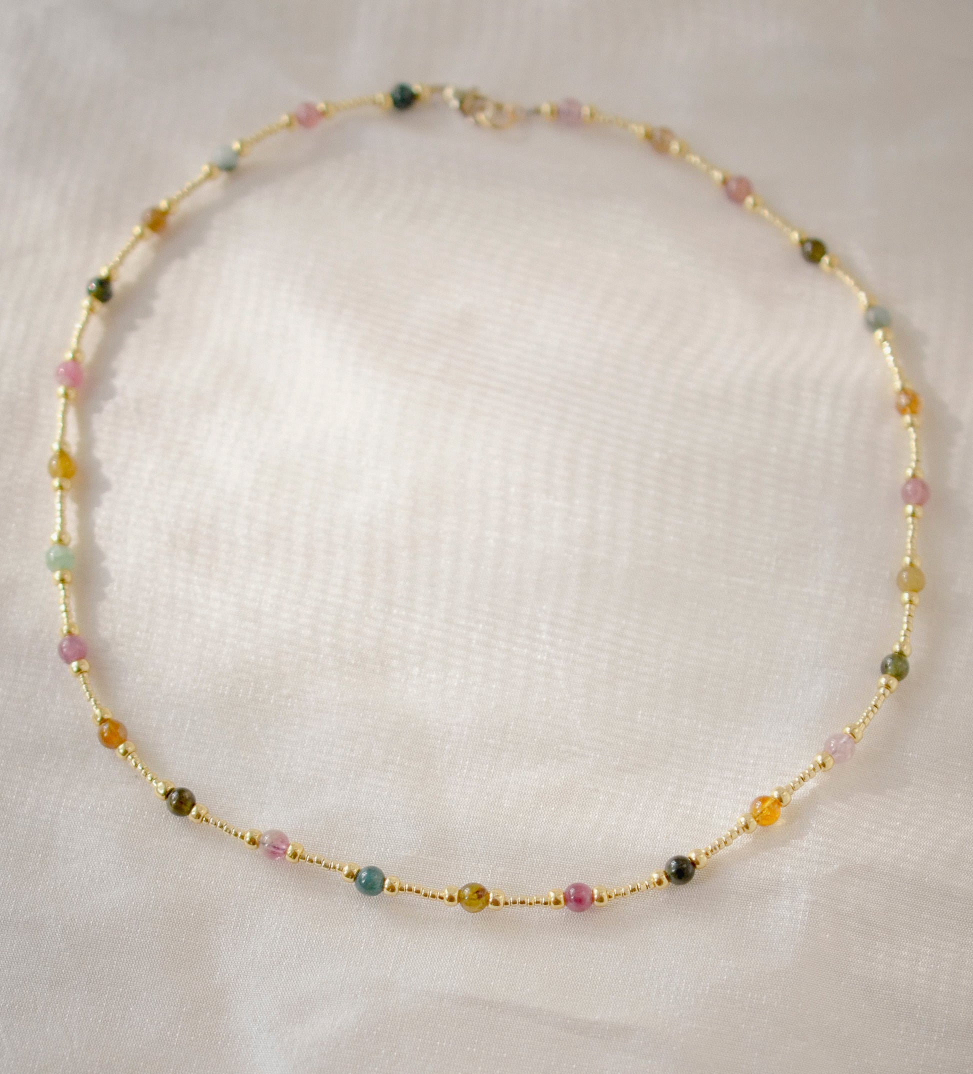 Multicolored, smooth polished Tourmaline gems hand-beaded with gold plated glass beads. Colors range from pink, green, brown, yellow, or black.