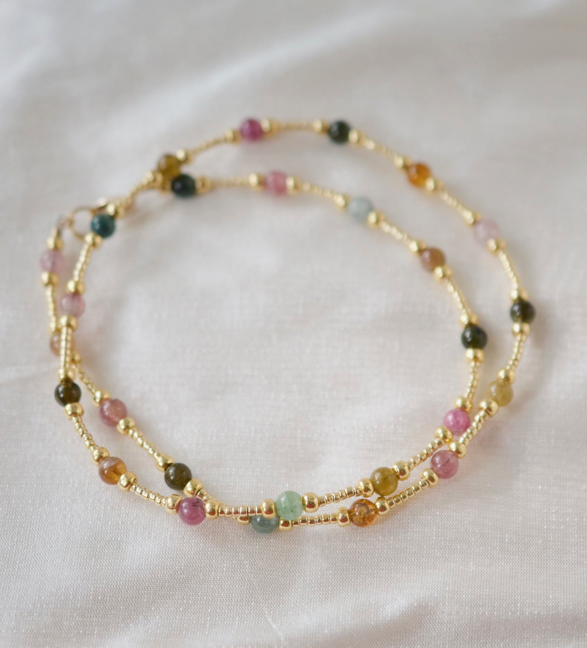 Multicolored, smooth polished Tourmaline gems hand-beaded with gold plated glass beads. Colors range from pink, green, brown, yellow, or black.