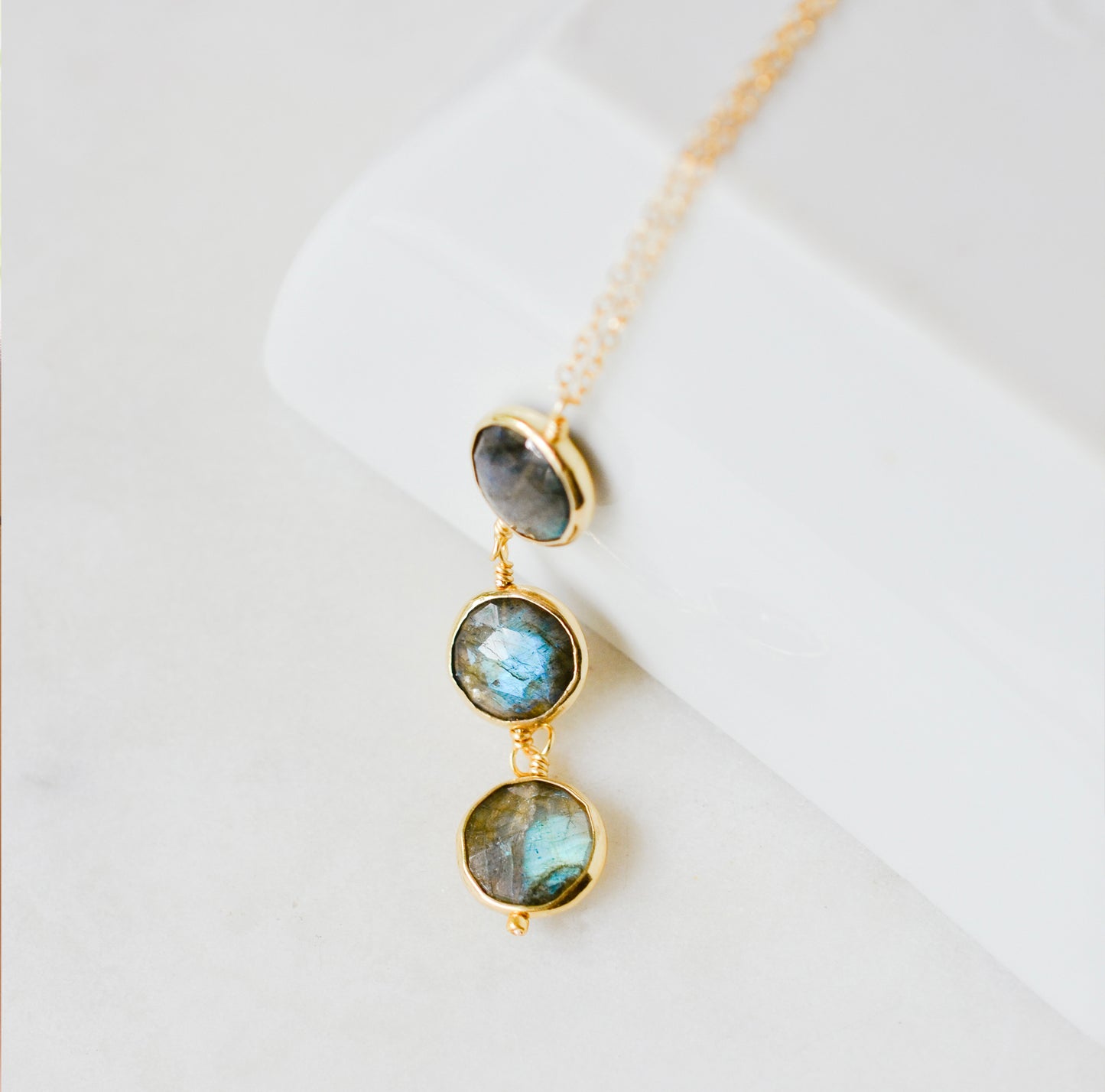 A delicate necklace with three natural labradorite stones on a 14k gold filled chain. This necklace is handmade in Connecticut by Gemnia Jewelry.