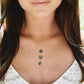 Woman wearing a gold necklace with three natural blue and green circle shaped labradorite gemstones suspended from a 14k gold filled chain. This handmade necklace is also available in sterling silver. 