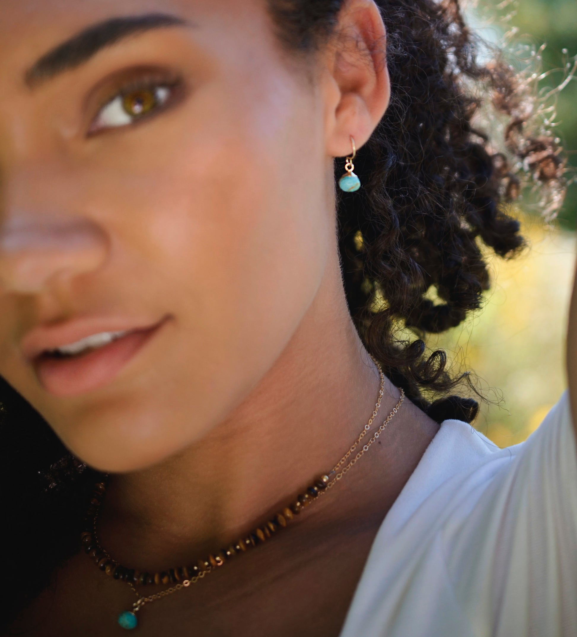 Small round turquoise faceted drops suspended from gold filled earwires. Each stone has a different matrix with light to dark brown coloring. Modeled image.