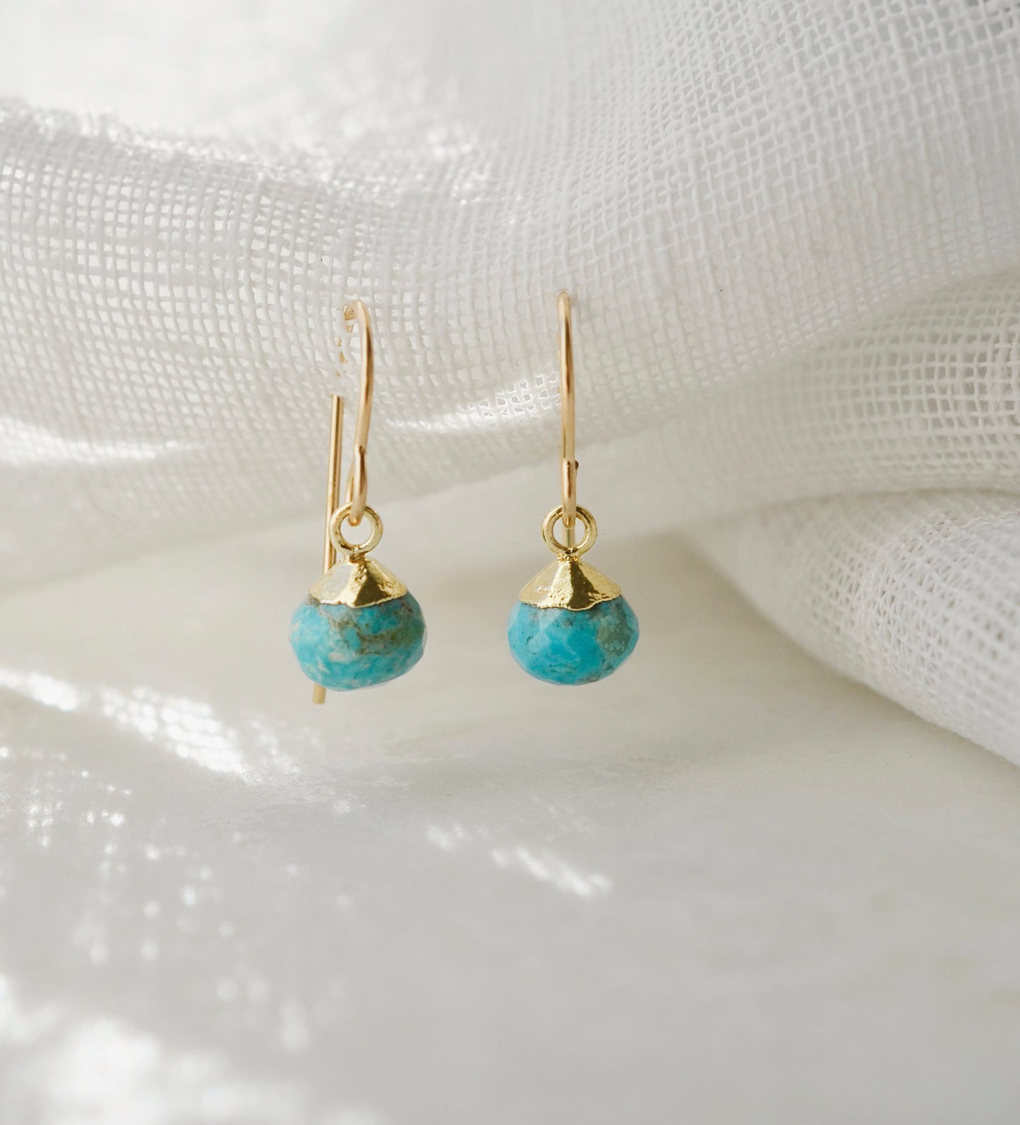 Small round turquoise faceted drops suspended from gold filled earwires. Each stone has a different matrix with light to dark brown coloring.