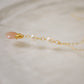 Side View. Two white semi-round pearls hang over a natural peach Moonstone faceted drop. The gold style pendant is shown.