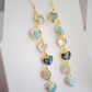 These handmade earrings feature blue and white natural stone hearts bezeled in gold. Each gemstone is a different color and includes: labradorite, larimar, mother of pearl, aquamarine, and rainbow moonstone. Long and light weight they make the perfect romantic gift. They are 3 inches long.
