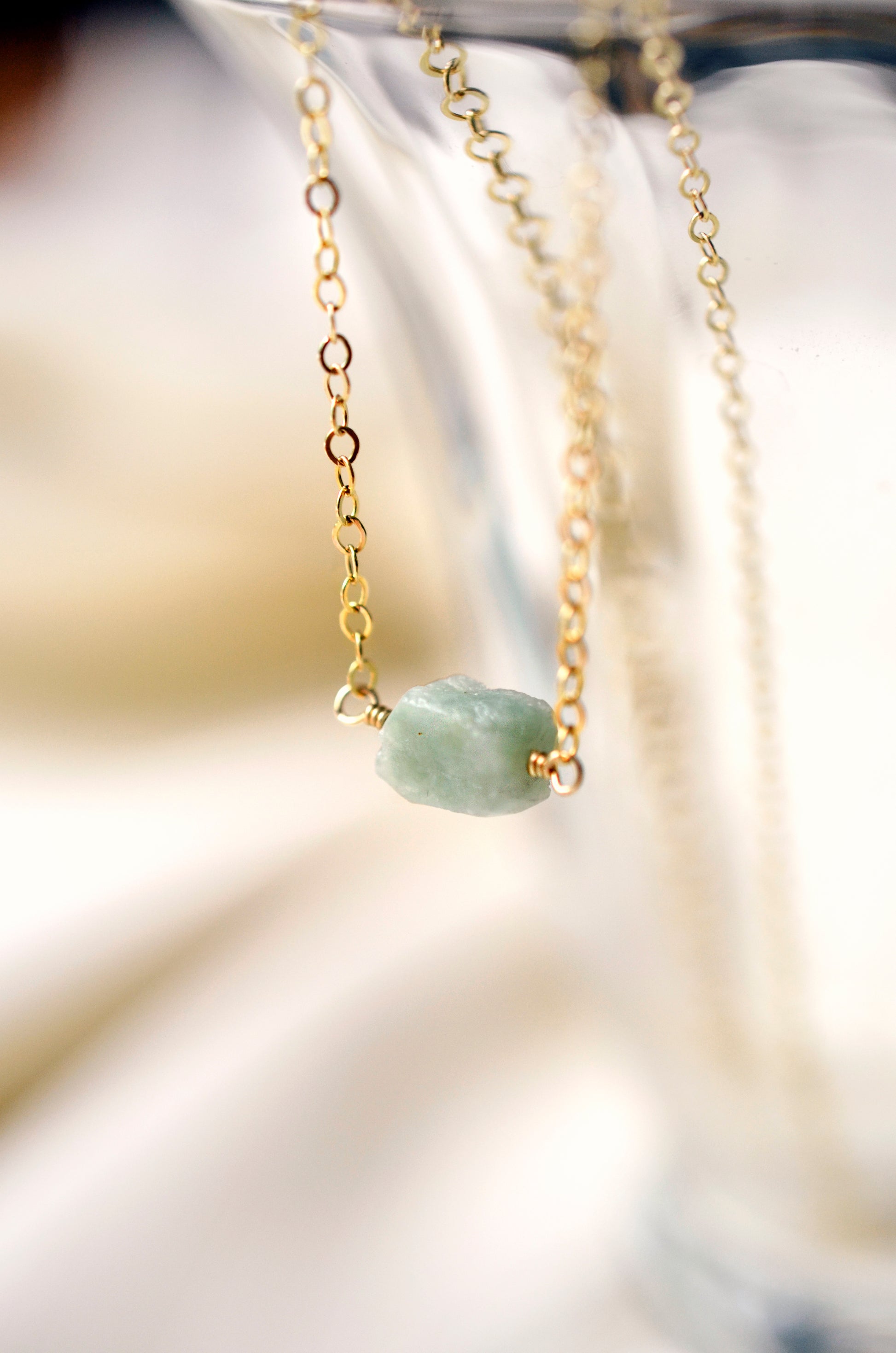 Pale green raw jade stone set onto a 14k gold filled chain. 