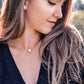A woman is wearing a natural white howlite necklace. The stone is round with natural gray marbling and set on a 14k gold filled chain. Also available in sterling silver. 