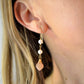 Two white semi-round pearls hang over natural peach Moonstone faceted drops. The gold style is shown. Modeled Image.