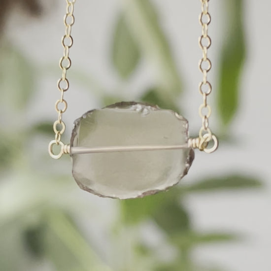 An irregular oval shape, smooth polished Smokey Quartz stone set onto a 14k gold filled chain. The stones edges are raw and irregular. Video.