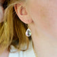 Close up of rainbow colored mystic topaz earrings in 14k gold filled. The stone is a teardrop shape. Modeled image.
